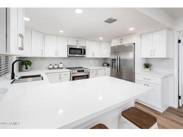 Modern white kitchen with island and stainless steel appliances at 11225 S Tomah St, Phoenix, AZ 85044