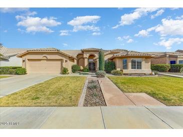 Single-story home with a landscaped yard, two-car garage, and inviting walkway at 18903 N 87Th Dr, Peoria, AZ 85382