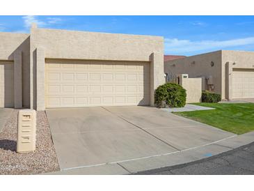 Beige stucco home featuring an attached garage and a well-maintained driveway and front garden at 2059 E Brown Rd # 23, Mesa, AZ 85213