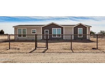 Tan and dark brown single-story house with a gated fence at 36747 W Harrison St, Tonopah, AZ 85354