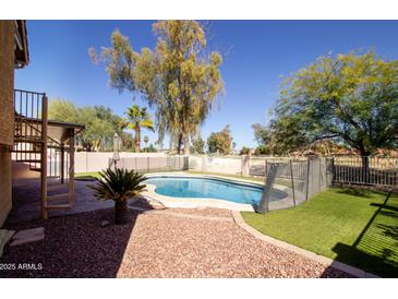 Sparkling pool featuring artificial turf, stone landscaping, and a secure safety fence at 11825 S 46Th St, Phoenix, AZ 85044
