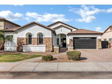 Inviting single-story home with stone accents, tile roof, well-manicured lawn, and paver driveway at 1612 E Zion Way, Chandler, AZ 85249