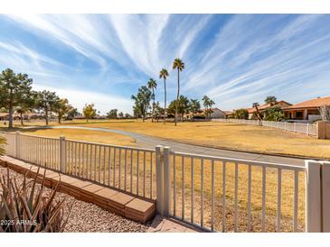 View of a lush green golf course from behind a white fence at 25432 S Queen Palm Dr, Sun Lakes, AZ 85248