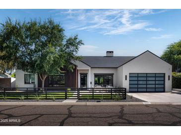 Modern farmhouse exterior with a white facade, dark wood accents, and a landscaped front yard at 3837 E Heatherbrae Dr, Phoenix, AZ 85018