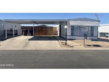 Single-wide manufactured home with carport and small front yard at 10951 N 91St Ave # 127, Peoria, AZ 85345