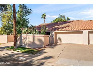 Tan stucco condo building with tile roof, two-car garage, and mature landscaping at 11192 N 109Th Pl, Scottsdale, AZ 85259