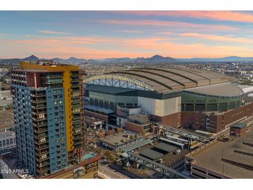 Stunning aerial view showcases a high-rise building near a stadium, with mountains in the distance under a vibrant sky at 310 S 4Th St # 908, Phoenix, AZ 85004