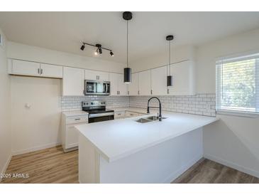 Modern white kitchen with stainless steel appliances and an island at 4720 E Belleview St, Phoenix, AZ 85008