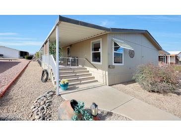 Tan mobile home exterior with covered porch, stairs, and landscaping at 11596 W Sierra Dawn -- # 132, Surprise, AZ 85378