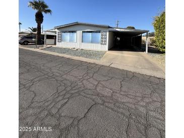 Single-wide mobile home with carport and mature palm tree at 120 N Val Vista Dr # 38, Mesa, AZ 85213