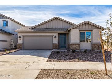 Single-story home with gray siding, stone accents, and a two-car garage at 16767 W Cavedale Dr, Surprise, AZ 85387