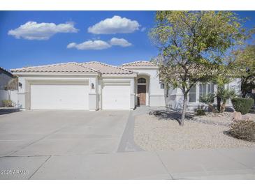 White single story home with a three car garage and desert landscaping at 7278 W Via Montoya Dr, Glendale, AZ 85310