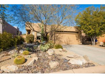 Desert landscape and single-story home with tan stucco exterior, and a two car garage at 9574 E Chuckwagon Ln, Scottsdale, AZ 85262