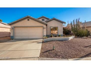 Single-story house with a beige exterior, attached garage, and desert landscaping at 14033 W Two Guns Trl, Surprise, AZ 85374