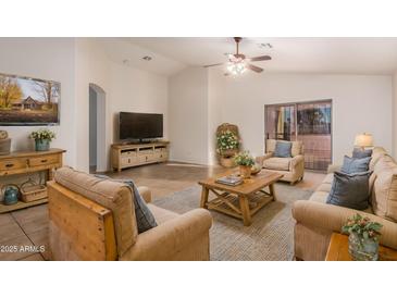 Bright living room features neutral furnishings, vaulted ceiling with ceiling fan, and sliding glass doors to patio at 14033 W Two Guns Trl, Surprise, AZ 85374