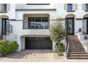 Two-story home with Spanish-style architecture, black garage door, and private staircase at 17680 N 77Th Pl, Scottsdale, AZ 85255