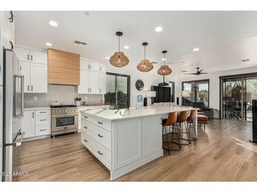 Bright kitchen featuring a large island with white countertops and shaker cabinets, stainless steel appliances, and modern pendant lighting at 1885 W Dion Dr, Phoenix, AZ 85086