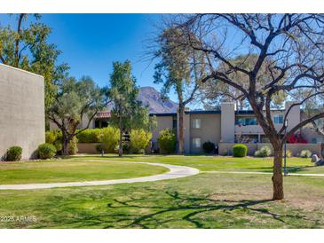 Scenic complex view showcasing lush green lawns, mature trees, and well-maintained buildings against a backdrop of blue skies at 4201 E Camelback Rd # 25, Phoenix, AZ 85018