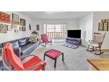 Bright living room with balcony access, comfy seating, and a large TV at 7910 E Camelback Rd # 312, Scottsdale, AZ 85251