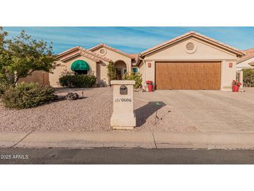 Tan house with brown garage door, green awning, and desert landscaping at 10606 E Hercules Dr, Sun Lakes, AZ 85248