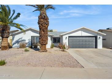 White brick house with gray garage door, landscaping, and palm trees at 4242 E Sacaton St, Phoenix, AZ 85044