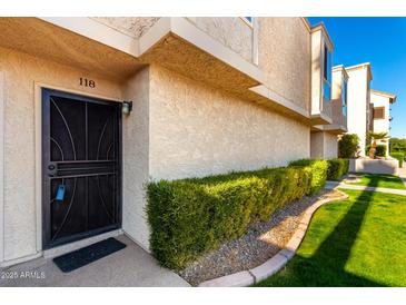 Exterior view of condo with a well-manicured lawn and a security door at 7910 E Thomas Rd # 118, Scottsdale, AZ 85251