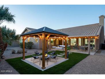Backyard patio with a pergola, fire pit, and artificial turf at 9439 E Palm Tree Dr, Scottsdale, AZ 85255