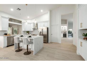 Modern kitchen with white cabinets, quartz countertops, and breakfast bar at 9439 E Palm Tree Dr, Scottsdale, AZ 85255