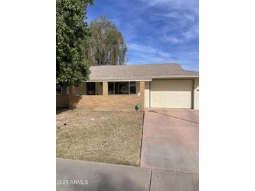 Ranch-style home with a two-car garage and mature landscaping at 10630 W Roundelay Cir, Sun City, AZ 85351