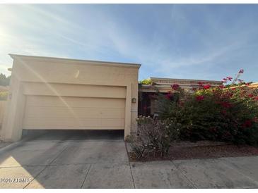 Tan house with two-car garage and red flowering bushes at 10846 N 11Th St, Phoenix, AZ 85020