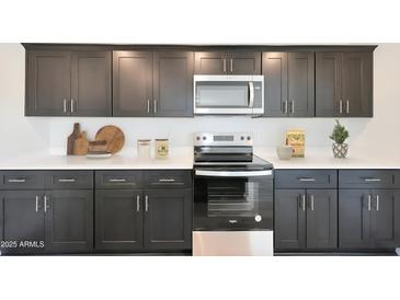 Modern kitchen with dark cabinetry, stainless steel appliances, and quartz countertops at 1321 W Inca Dr, Coolidge, AZ 85128