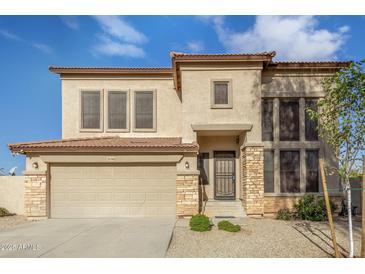 Two-story house with tan exterior, stone accents, and a three-car garage at 28396 N Tourmaline Dr, San Tan Valley, AZ 85143