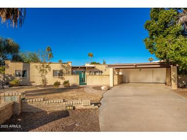 Single-story home with a large driveway and mature landscaping at 102 W El Caminito Dr, Phoenix, AZ 85021