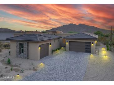 Stunning front exterior featuring a gray brick driveway and a two-car garage against a backdrop of mountain views at 37178 N Winding Wash Trl, Carefree, AZ 85377