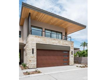 Contemporary two-story home featuring a stone facade, balcony, and a modern wood garage door at 4575 N Phoenician Blvd # 4, Scottsdale, AZ 85251