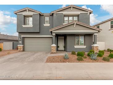 Two-story home with gray siding, stone accents, and a two-car garage at 9354 E Sector Dr, Mesa, AZ 85212