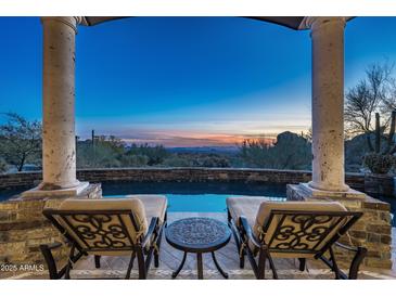 Inviting swimming pool framed by stately columns offers stunning desert views at sunset at 10922 E Purple Aster Way, Scottsdale, AZ 85262