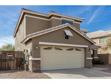 Two-story house with beige exterior, a large garage, and a well-maintained front yard at 224 S 151St Ave, Goodyear, AZ 85338