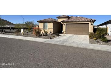 Charming single Gathering home featuring a tan exterior, brown garage door and low maintenance desert landscaping at 6516 W Madre Del Oro Dr, Phoenix, AZ 85083