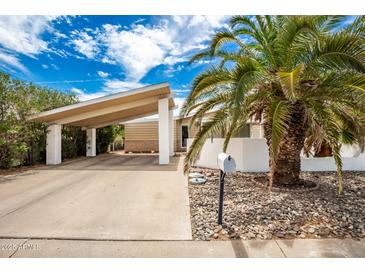 Mid-century home with carport, palm trees, and rock landscaping at 10461 W Devonshire Ave, Phoenix, AZ 85037