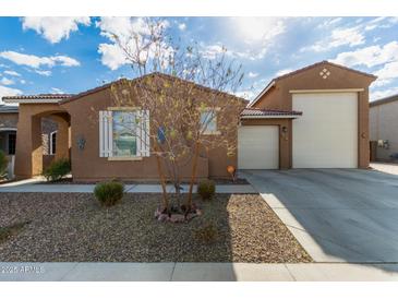 Beige house with a three-car garage and desert landscaping at 14353 W Ventura St, Surprise, AZ 85379