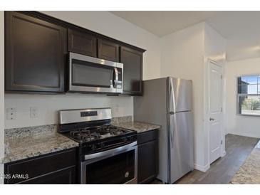 Modern kitchen with stainless steel appliances and granite countertops at 20249 W Woodlands Ave, Buckeye, AZ 85326