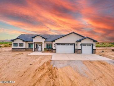 Stunning ranch-style house with a three-car garage and desert landscaping at 23527 W Estes Way, Buckeye, AZ 85326