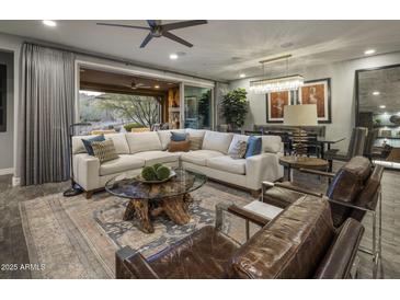 Spacious living room features a large sectional sofa, fireplace and sliding glass doors leading to the backyard at 26698 N 104Th Way, Scottsdale, AZ 85262