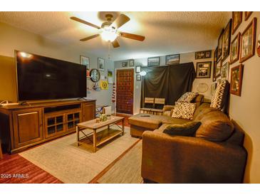 Cozy living room featuring a sectional sofa, large TV, and wood-look floors at 17241 N 16Th Dr # 10, Phoenix, AZ 85023