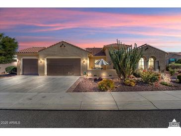 Inviting tan home with a three car garage, desert landscaping, and a charming patio area, perfect for outdoor living at 20369 N 272Nd Ave, Buckeye, AZ 85396