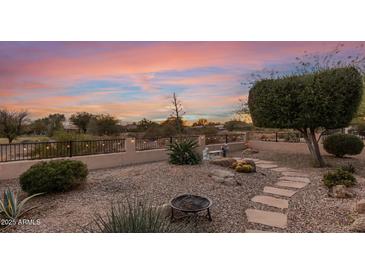 Landscaped backyard with fire pit, stone pathway, and desert plants at sunset at 23187 W Lasso Ln, Buckeye, AZ 85326