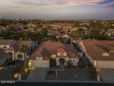 Expansive aerial view of a neighborhood showcasing neatly landscaped homes and tranquil streets at twilight at 10048 E Emerald Dr, Sun Lakes, AZ 85248