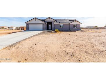 Single-story house with gray exterior, solar panels, and a long driveway at 1529 S 357Th Ave, Tonopah, AZ 85354