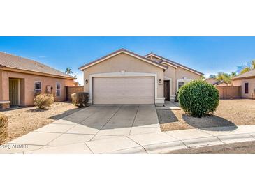 Tan house with a two-car garage and well-manicured landscaping at 15365 W Caribbean Ln, Surprise, AZ 85379